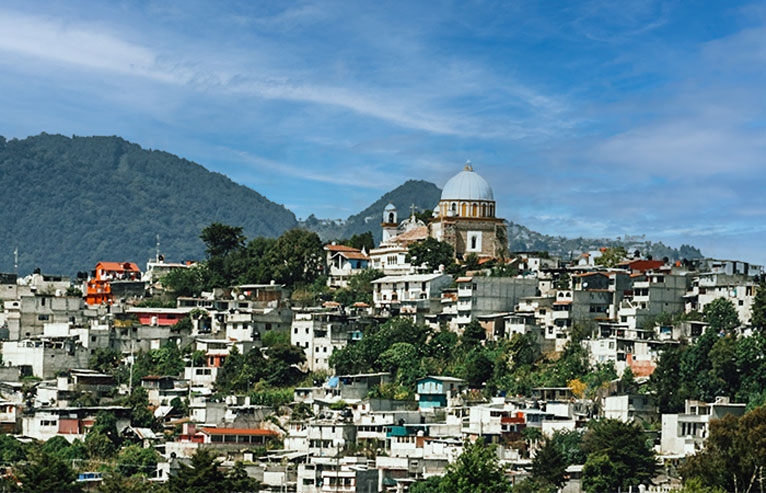 Kolonialstadt San Cristóbal de las Casas mit farbigen Häusern, Kirche und umliegenden Bergen in Chiapas