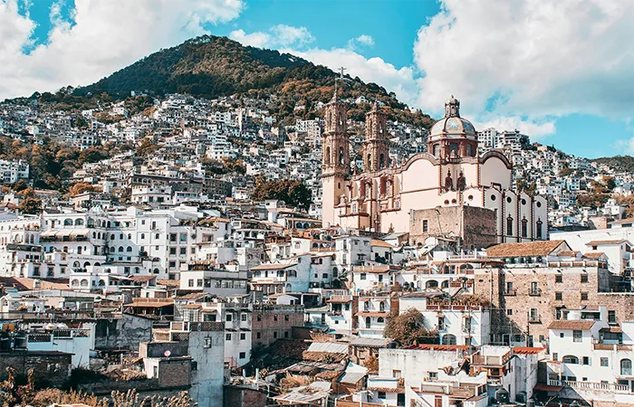 Kolonialstadt Taxco mit dichter weißer Bebauung und markanter Kuppelkirche im bergigen Hochland von Guerrero