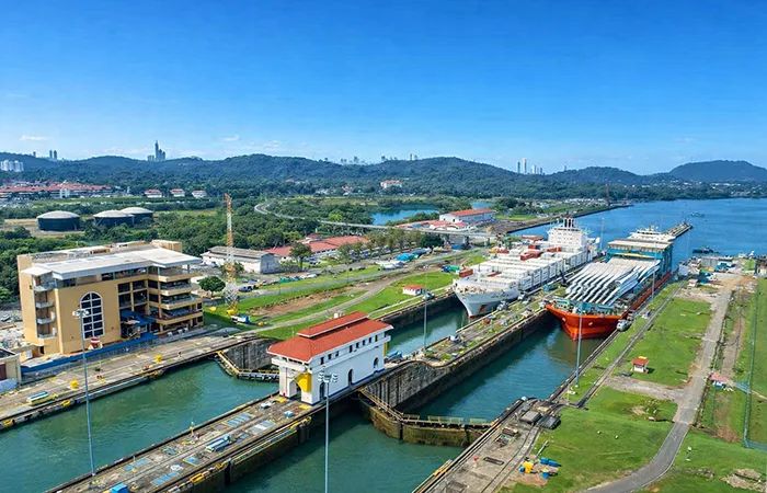 Esclusas del Canal de Panamá con buques portacontenedores, estanques de agua y paisaje verde ondulado