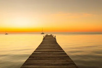 Jetée en bois menant tranquillement à la mer au coucher du soleil, symbole d'un nouveau départ et de nouvelles perspectives